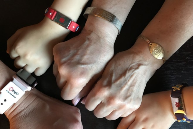 a group of hands with medical bracelets
